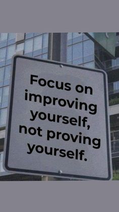 a white sign that says focus on imppoing yourself, not providing yourself in front of some tall buildings