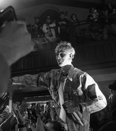 black and white photograph of a man standing in front of a crowd with his arms out