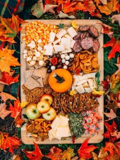 a wooden tray filled with lots of different types of food and nuts on top of leaves