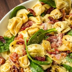 a bowl filled with pasta and spinach covered in cheese, meat and seasoning