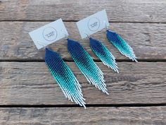 three pairs of blue and white beaded earrings with fringes on wooden table top