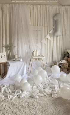 white balloons are scattered on the floor in front of curtains