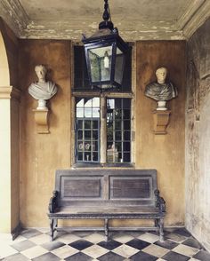 a bench sitting in front of a window next to busturines on the wall