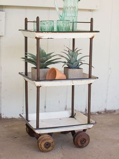 a small cart with plants on it sitting in front of a wall