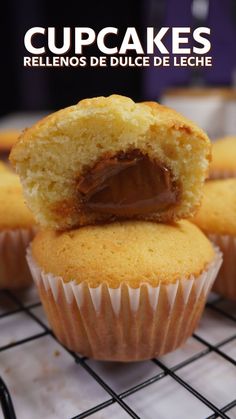 some cupcakes are on a cooling rack and one has a bite taken out