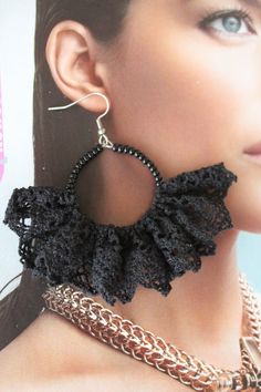 a woman wearing black crochet earrings with chains around her neck and earring