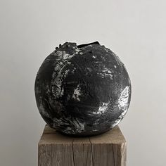 a black vase sitting on top of a wooden block