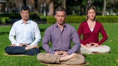 three people are sitting on the grass in yoga poses and meditates with their hands together