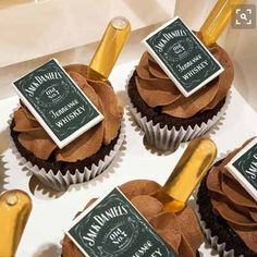 six chocolate cupcakes with champagne bottles on top