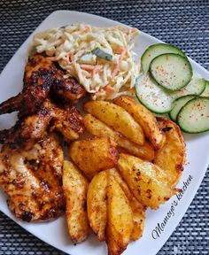 a white plate topped with chicken, potatoes and cucumbers