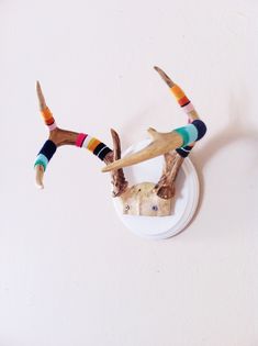 two deer antlers with colorful socks on their heads are mounted to the side of a wall