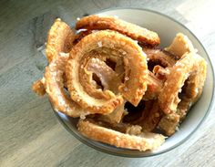 a bowl filled with fried onion rings on top of a wooden table