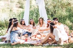 a group of women sitting on top of a grass covered field next to each other