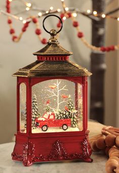 a red lantern sitting on top of a table filled with christmas decorations and lights in front of a tree