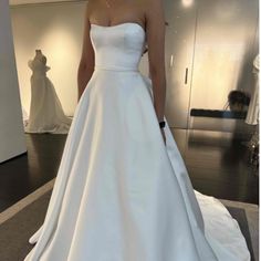 a woman in a white wedding dress is standing on a black carpet and looking at the camera