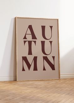 an art print with the word autumn on it in brown and tan colors against a white wall