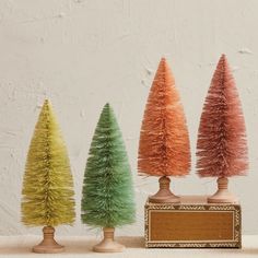 three small trees are lined up in different colors