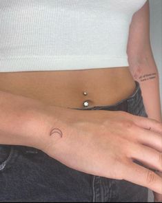 a woman's stomach with a small crescent tattoo on her left arm and the moon behind her belly