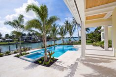 an outdoor swimming pool with palm trees and water in the back ground, surrounded by lush greenery