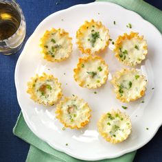 small appetizers on a white plate next to a glass of wine and napkin