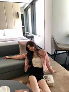 a woman sitting on the floor in front of a couch next to a table and chair