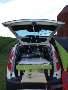 the back end of a van with an open trunk and sleeping bag attached to it