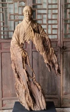 a statue of an old man holding a bird in front of a wooden paneled door