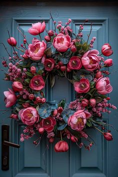 a blue door with a pink wreath and flowers hanging on it's front door