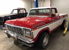 an old red and white truck parked in a garage