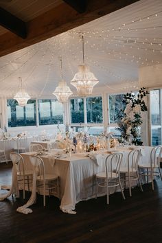 a room filled with lots of tables covered in white table cloths and chandeliers