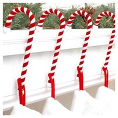 three candy canes are hanging from a window sill with snow on the windowsill