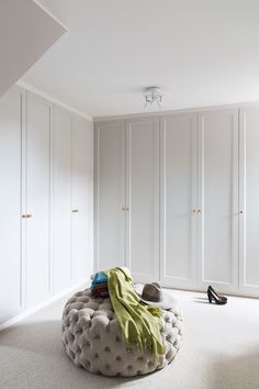 a bedroom with white closets and a round ottoman