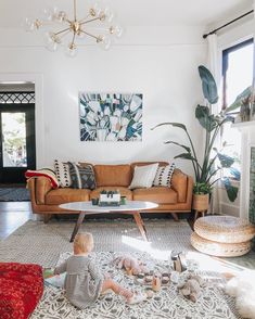 a living room filled with furniture and a baby sitting on the floor in front of a fire place