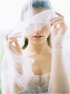 a woman is holding her veil over her face