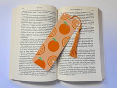 an open book with oranges and tassel on the front cover is shown in this image