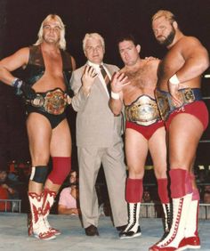 three men standing next to each other in wrestling gear