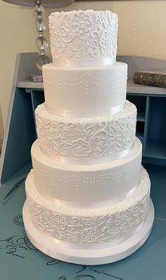 a large white wedding cake sitting on top of a blue tablecloth covered countertop