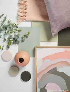 an arrangement of art, flowers and other items on a table with a pink pillow