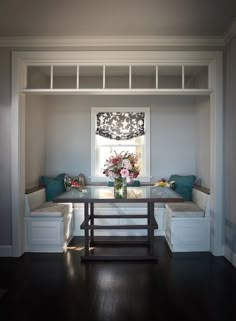 a window seat in the corner of a room with a table and bench underneath it