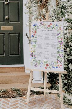 an easel stands in front of a door with a seating chart on it