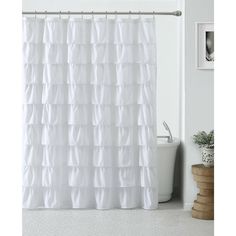 a white shower curtain with ruffles on it in a bathroom next to a toilet