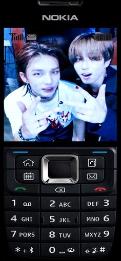 an old nokia cell phone with two young men on it's screen and one pointing at the camera