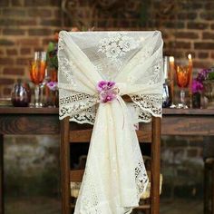 an image of a table setting with white linens and flowers on it, tied to the back of a chair