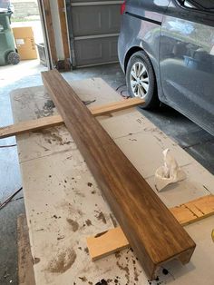 a car is parked in a garage next to some wood planks that have been placed on the floor