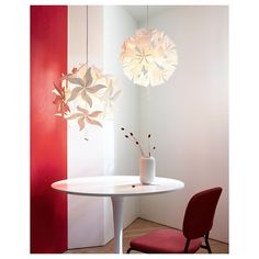 a white table and red chair in a room with two lights hanging from the ceiling