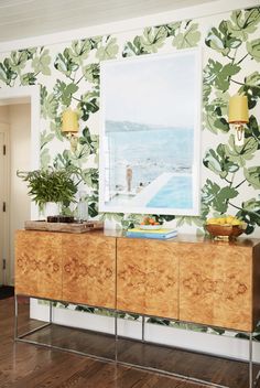 a wallpapered room with a painting on the wall and a sideboard in front of it