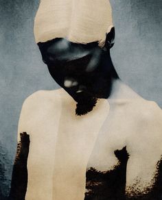 a woman's face is covered in black and white paint, as she stands with her back turned to the camera