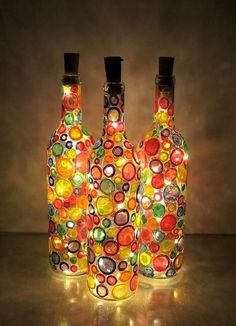 three glass bottles with lights inside them on a table