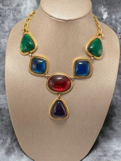 "Of course this would be a masterpiece by Kenneth J Lane This is the necklace from the Caprianti collection by KJL. This necklace showcases jewel-tone \"jelly belly\" cabochons that mimic those from the House of Gripoix. The cabochons are made of translucent jewel-tone colored Lucite, which lets the textured metal within allow them to appear to shimmer. This necklace is shown in the book \"SHAMELESSLY: Jewelry from Kenneth J Lane\" by Nancy Schiffer on page 192. Hallmark:  KJL for Avon Measures: Multicolor Cabochon Costume Jewelry, Elegant Multicolor Cabochon Necklaces, Vintage Multicolor Cabochon Jewelry, Multicolor Metal Necklaces For Collectors, Multicolor Costume Jewelry Necklace For Collectors, Metal Cabochon Necklace In Costume Jewelry Style, Jewel Tone Colors, Book Pieces, Sun City