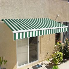 an awning on the side of a building in front of flowers and plants outside